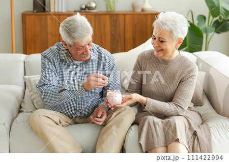 Saving money investment for future. Senior adult mature couple holding piggy bank putting money coin. Old man woman counting saving money planning retirement budget. Saving investment banking concept Saving money investment for future. Senior adult mature couple holding piggy bank putting money coin. Old man woman counting saving money planning retirement budget. Saving investment banking concept 111422994