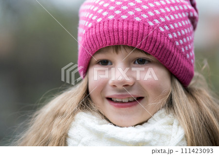 Pretty child girl in warm knitted winter clothes outdoors. 111423093