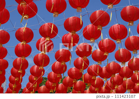 A collection of red paper lanterns hanging against a clear blue sky. A collection of red paper lanterns hanging against a clear blue sky. 111423107