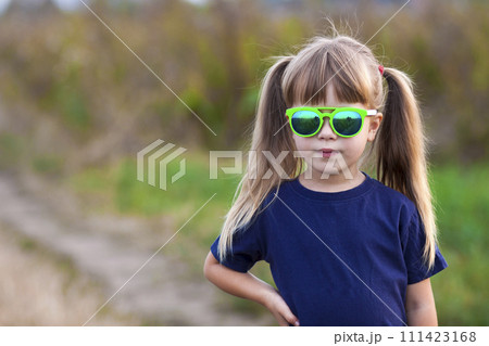 Portrait of little fashionable girl in green sunglasses outdoors 111423168