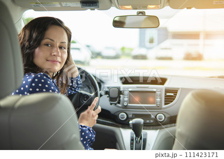 Young stylish woman driver sitting behind steering wheel of her car. Driving vehicle concept 111423171