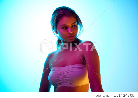 Elegant beautiful young girl with ponytail, wearing white op, standing against gradient studio background in neon light. Beauty makeup campaign Elegant beautiful young girl with ponytail, wearing white op, standing against gradient studio background in neon light. Beauty makeup campaign 111424509
