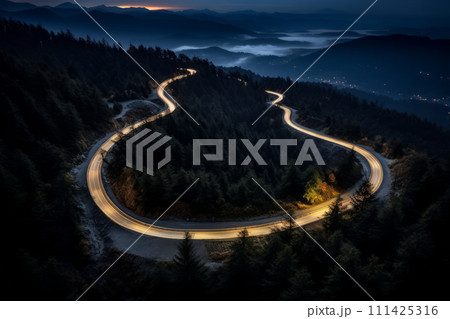 Curvy mountain road with trailing lights at night 111425316