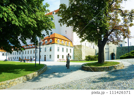 White castle building in Bratislava on a sunny day and a tourist White castle building in Bratislava on a sunny day and a tourist 111426371