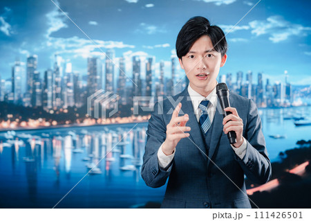 野外でマイクを使って話すスーツを着た男性 111426501