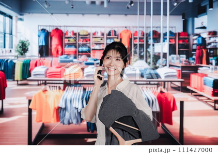 服屋さんで買い物をする若い女性 111427000