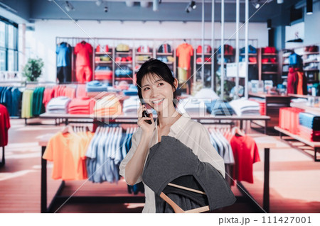 服屋さんで買い物をする若い女性 111427001