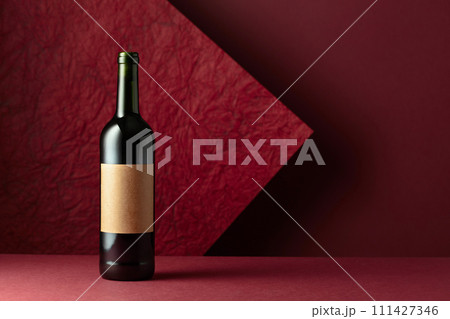 Bottle of red wine on a red background. 111427346