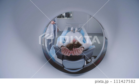 Woman lies on CT or PET or MRI scan bed and moves in machine Woman lies on CT or PET or MRI scan bed and moves in machine 111427582