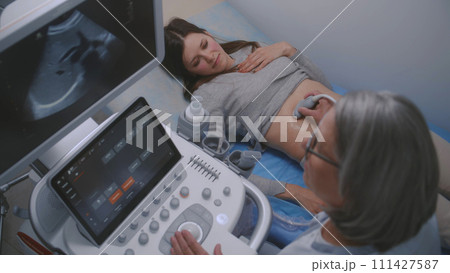 Female doctor conducts ultrasound diagnostics using sonography machine 111427587
