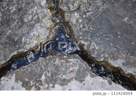 a deep crack in the road surface is filled with water after rain a deep crack in the road surface is filled with water after rain 111428004
