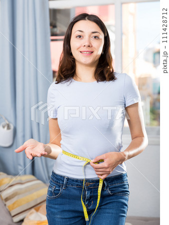 Slim glad young woman measuring waist with measuring tape 111428712