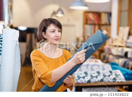 Brunette choosing fabric in store 111428822