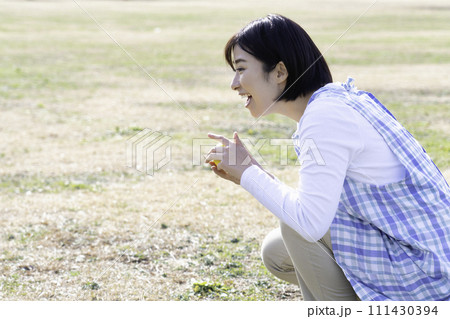 園外保育で公園の芝生で遊ぶ女性保育士 111430394