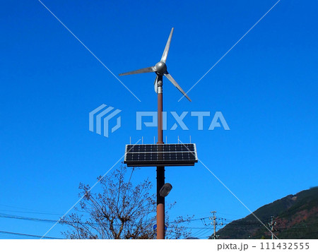 青空の下に設置された小型風力発電と太陽光パネルのハイブリッド街路灯 111432555