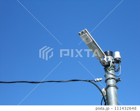 青空の下に設置されたLED防犯灯と電柱のクローズアップ 111432648