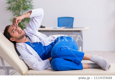 Young male doctor being tired after night shift Young male doctor being tired after night shift 111435688