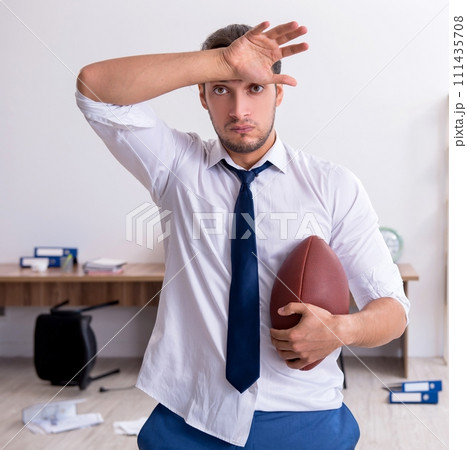 Young male employee throwing rugby ball in the office 111435708