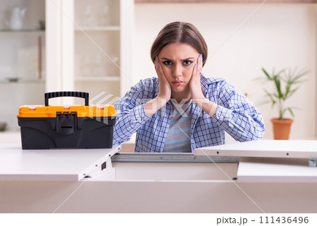 Young beautiful woman assembling furniture at home 111436496