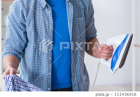 Young man husband doing clothing ironing at home Young man husband doing clothing ironing at home 111436916