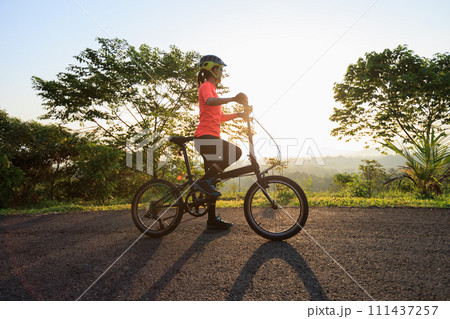 Riding folding bike on sunny mountain top road 111437257