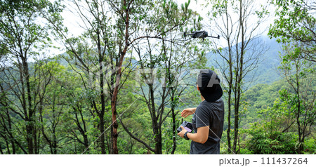 People remote control a flying drone in summer forest People remote control a flying drone in summer forest 111437264