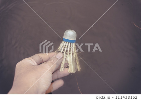 A hand dipped a broken racket ball into the water A hand dipped a broken racket ball into the water 111438162