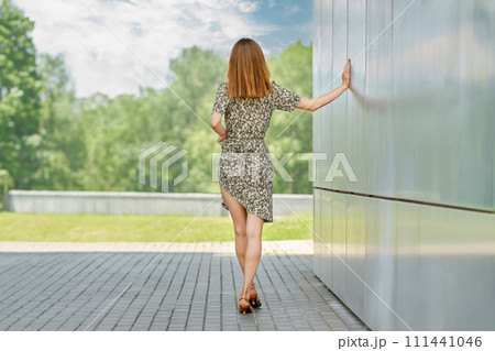 Back view of young woman in a patterned spring dress 111441046