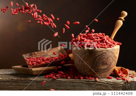 Dried goji berries in wooden bowl on a brown background. Dried goji berries in wooden bowl on a brown background. 111442409