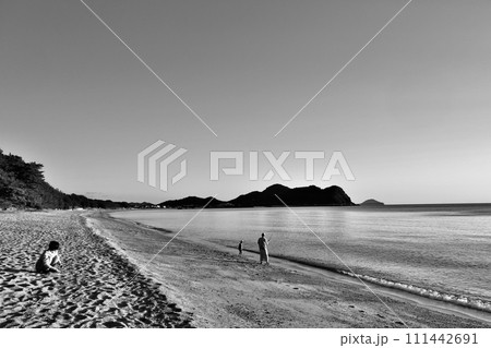 秋の連休を海岸で遊ぶ親子連れの白黒写真 111442691