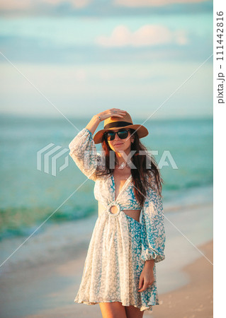 Young beautiful woman at straw hat on the beach at sunset Young beautiful woman at straw hat on the beach at sunset 111442816