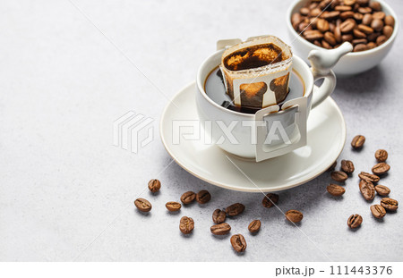 Drip coffee bag with ground coffee in cup Drip coffee bag with ground coffee in cup 111443376