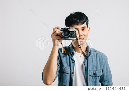 Excitement fills the air as a young man poses for a vintage camera, ready to be photographed. Studio shot isolated on white background. The result is a picture that defines glamour 111444421