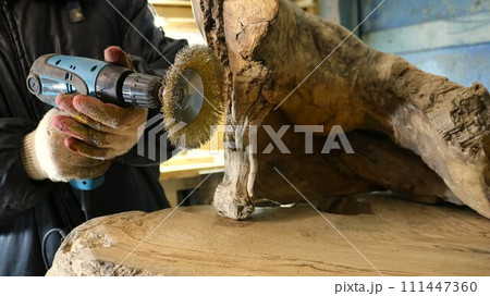 processing wood with a sander with a metal round bristle disk in a carpenter's workshop, sanding a piece of solid wood in the process of producing wooden carpentry processing wood with a sander with a metal round bristle disk in a carpenter's workshop, sanding a piece of solid wood in the process of producing wooden carpentry 111447360