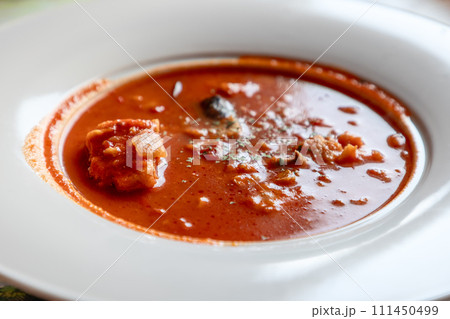 Traditional salt cod stew from Lofoten, rich tomato base, in a white serving bowl 111450499