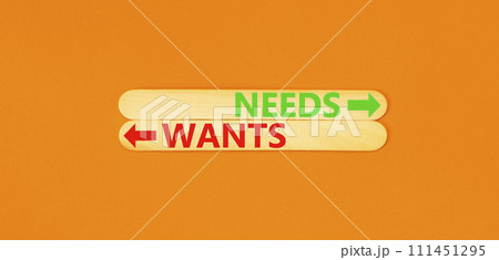 Needs or wants symbol. Concept word Needs or Wants on beautiful wooden stick. Beautiful orange table orange background. Business and needs or wants concept. Copy space. 111451295
