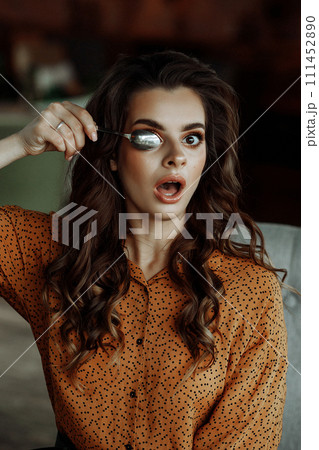 Playful woman covering eye with spoon. Playful woman covering eye with spoon. 111452890