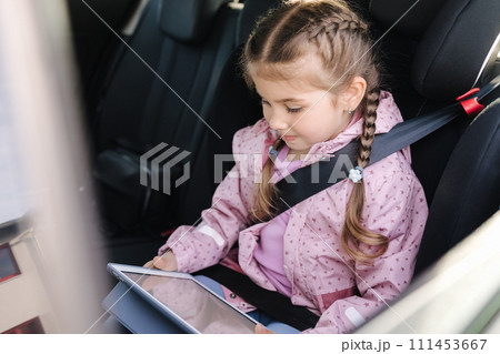 Cute little girl use tablet in car seat on the way to the kindergarten 111453667