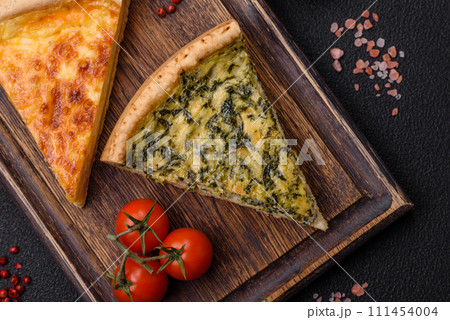 Delicious crispy quiche cut into slices with cheese, broccoli, tomatoes 111454004