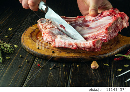 Close-up of a man hands slicing meat ribs on a cutting board before preparing shish kebab. Asian cuisine 111454574