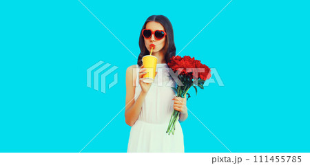 Portrait of beautiful woman with bouquet of red rose flowers drinking juice 111455785