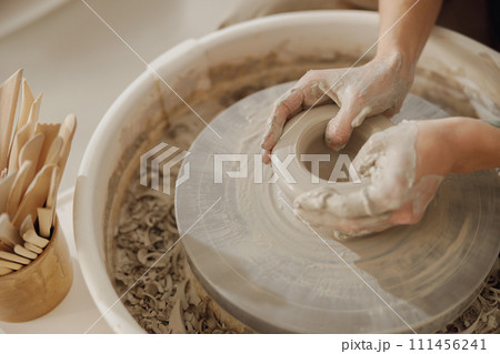 Close up of artisan's hands shaping clay bowl in pottery studio. Pottery art and creativity Close up of artisan's hands shaping clay bowl in pottery studio. Pottery art and creativity 111456241
