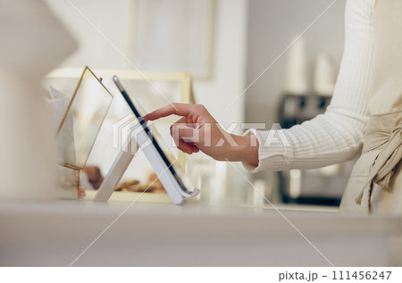 Close up of barista standing at the counter in coffee shop and takes orders from client Close up of barista standing at the counter in coffee shop and takes orders from client 111456247