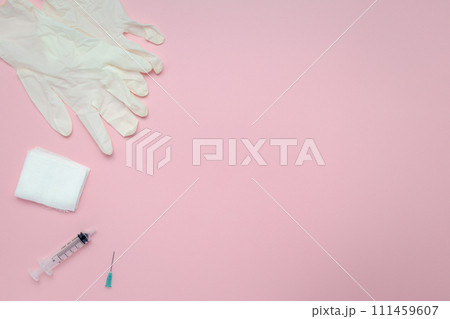 Flat lay of syringes, gauze, and latex gloves on a pink background Flat lay of syringes, gauze, and latex gloves on a pink background 111459607