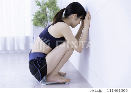 トレーニング後に体重を計って落ち込むミドル女性 111461306