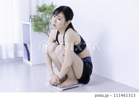 トレーニング後に体重を計って落ち込むミドル女性 111461313