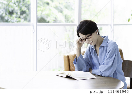 リビングで音楽を聴きながら本を読むミドルの女性 111461946