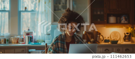 Woman pay tax online sitting at a kitchen table staring at a laptop screen showing tax preparation software 111462653