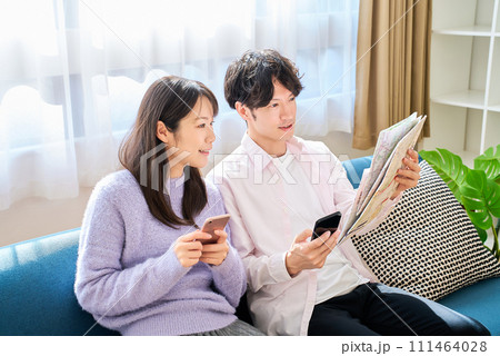 地図とスマートフォンを持って話す男女 地図とスマートフォンを持って話す男女 111464028