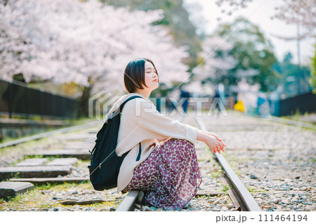 春の京都観光でインクラインの線路に座る女性 111464194